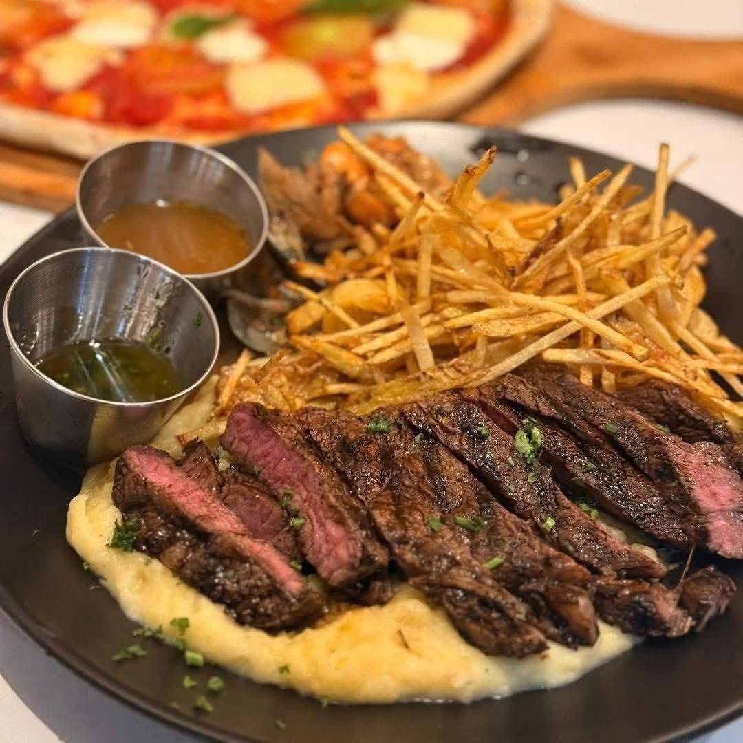 Sliced steak served with fries and sauces