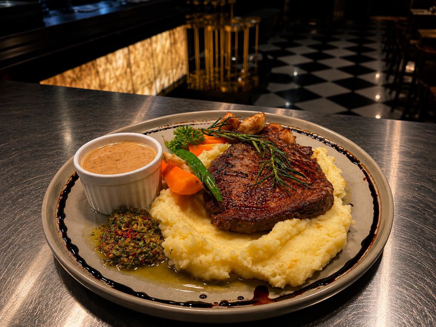 Steak served over mashed potatoes with vegetables