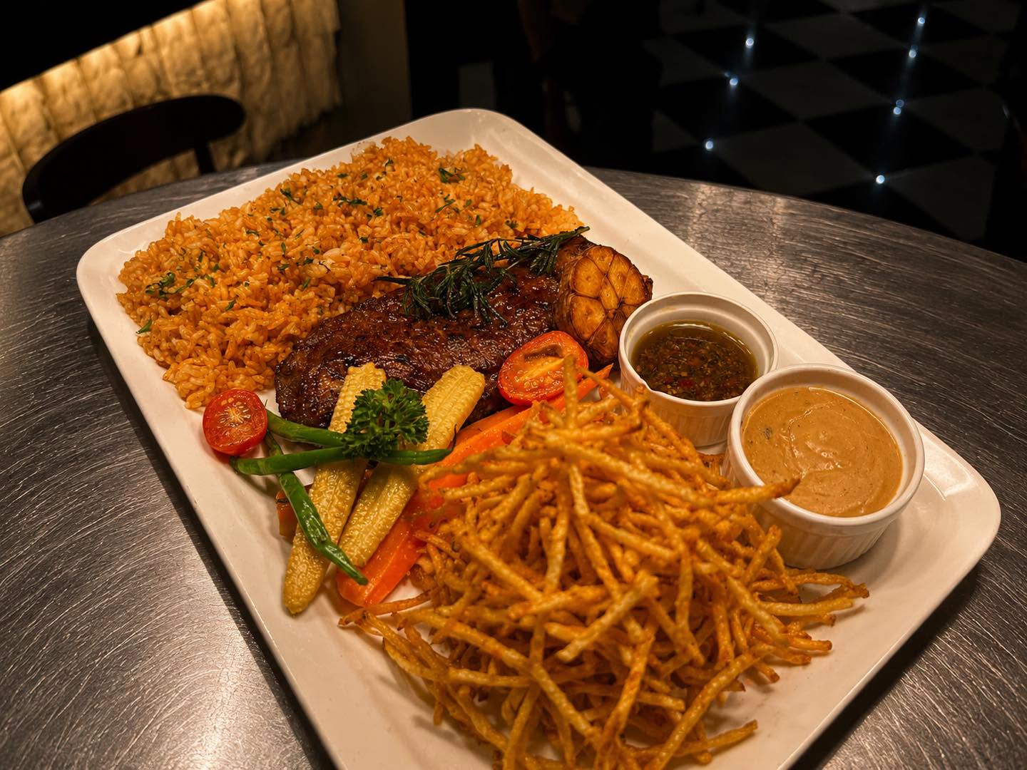 Steak platter with rice, vegetables, fries, and sauces