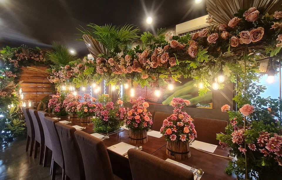 Long dining table surrounded by floral decorations
