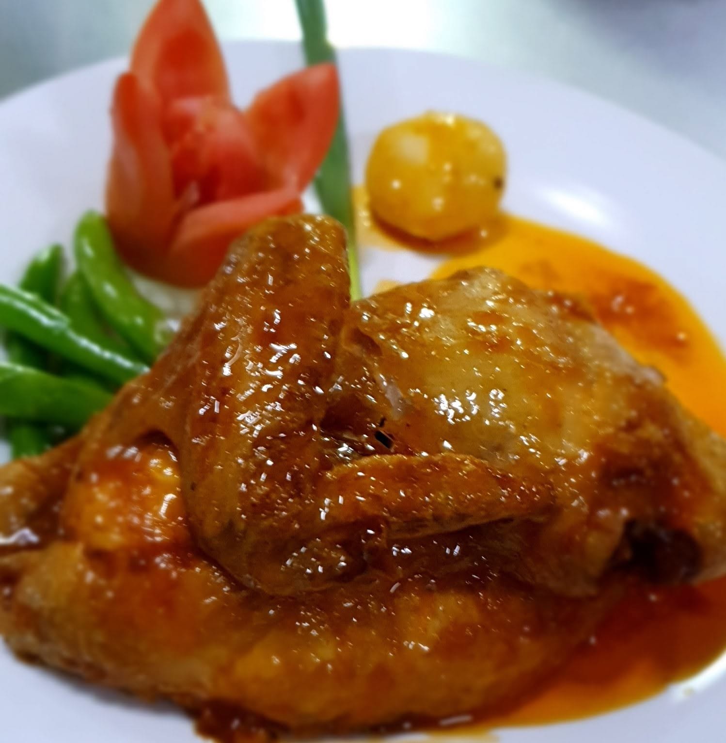 Chicken covered in sauce and served with vegetables
