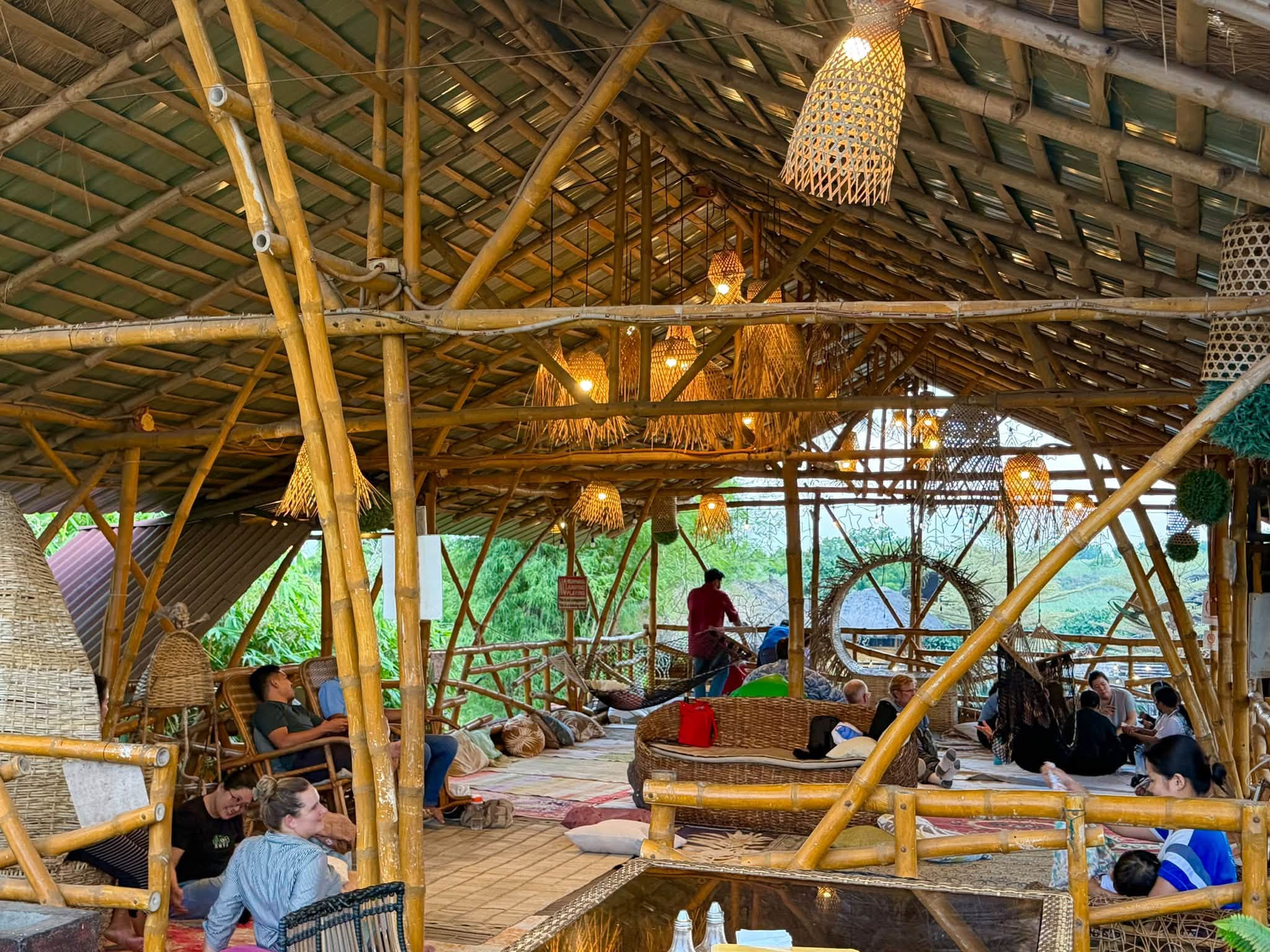 Guests relaxing under woven lamps in the bamboo pavilion at D’ Garden at Calatao