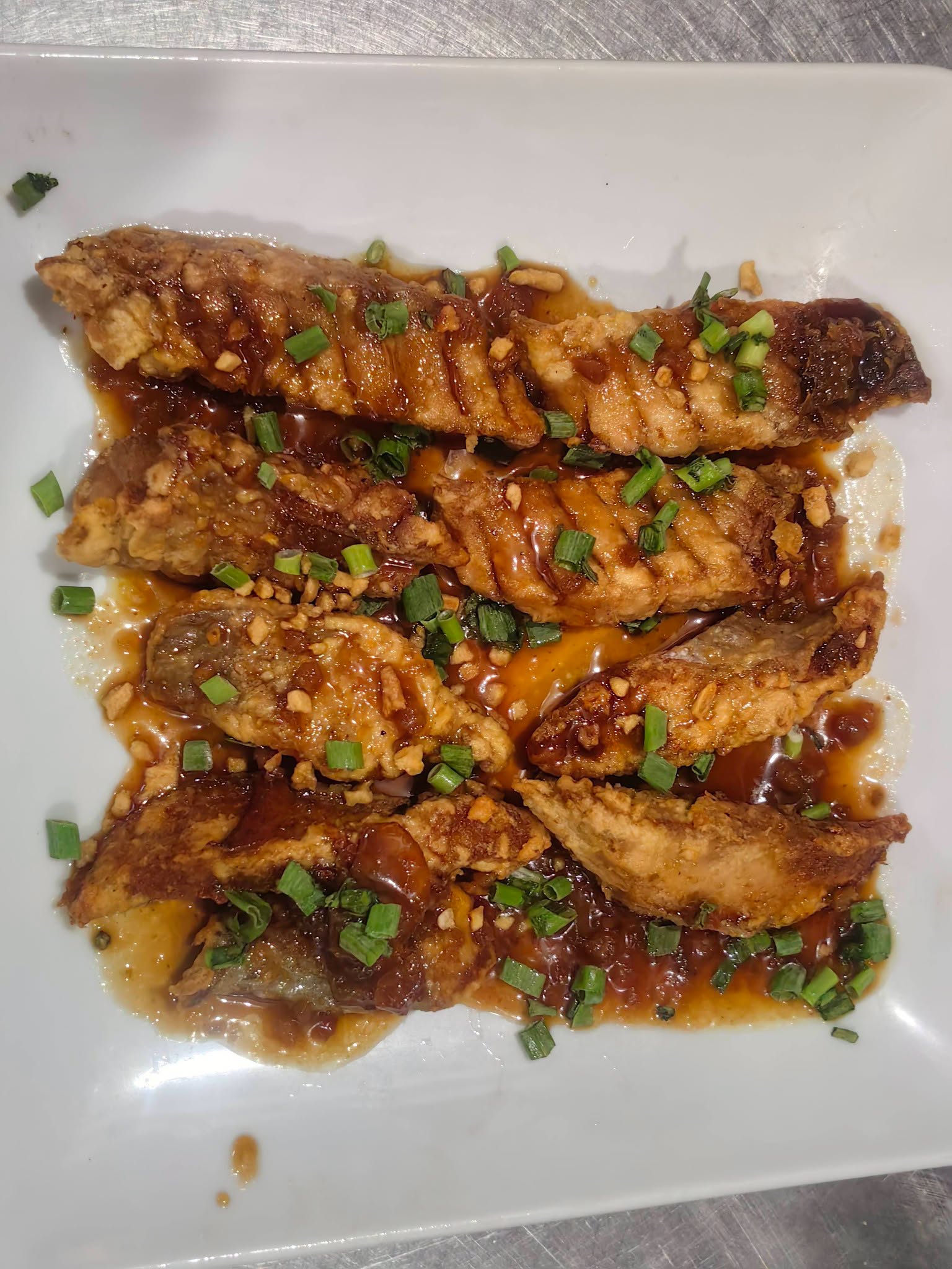 Sauced fish pieces topped with spring onions photographed at D’ Garden at Calatao