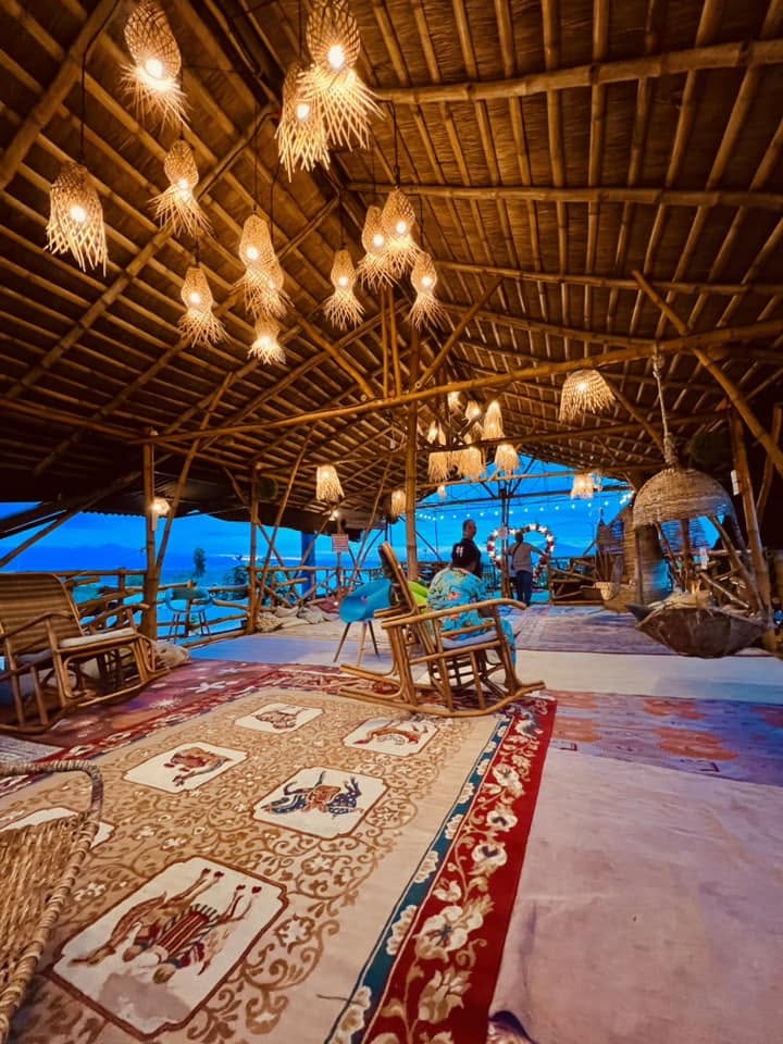 Rugs and rocking chairs inside the lit bamboo pavilion at D’ Garden at Calatao