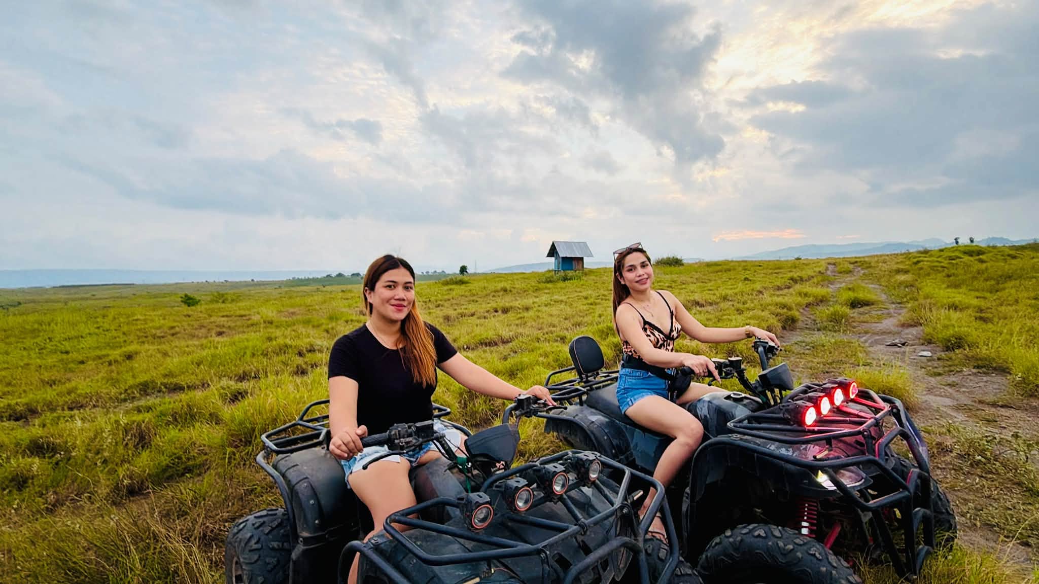 Two visitors seated on ATVs in an open field at D’ Garden at Calatao