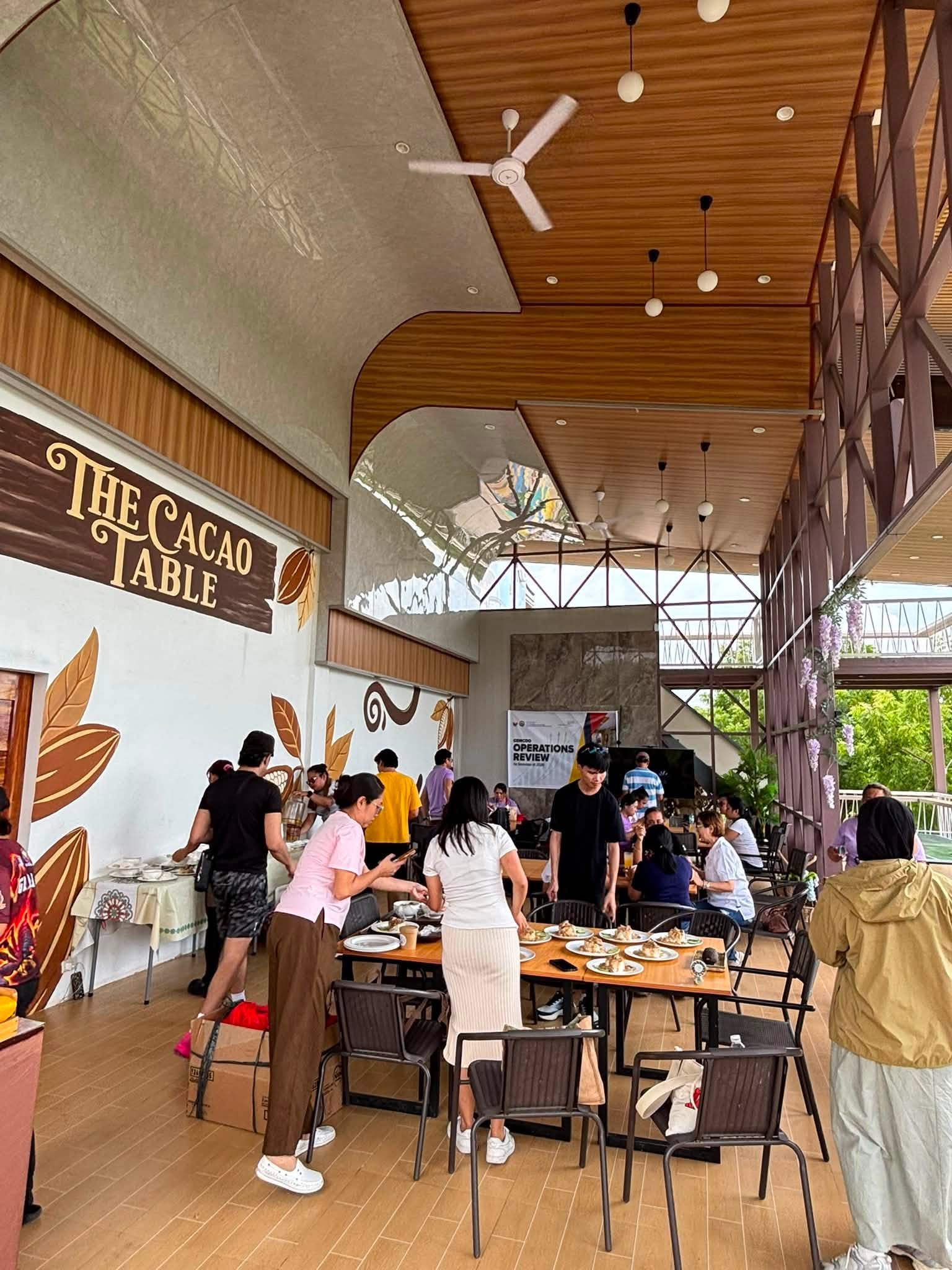 Visitors dining beside a wall marked The Cacao Table