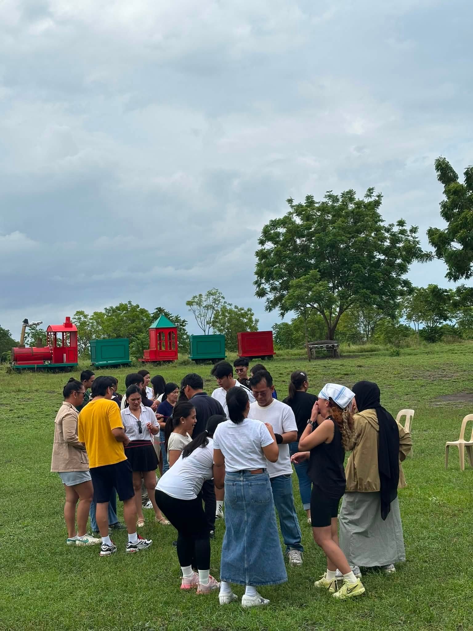 Group gathered on the green outdoor grounds near a colorful train display