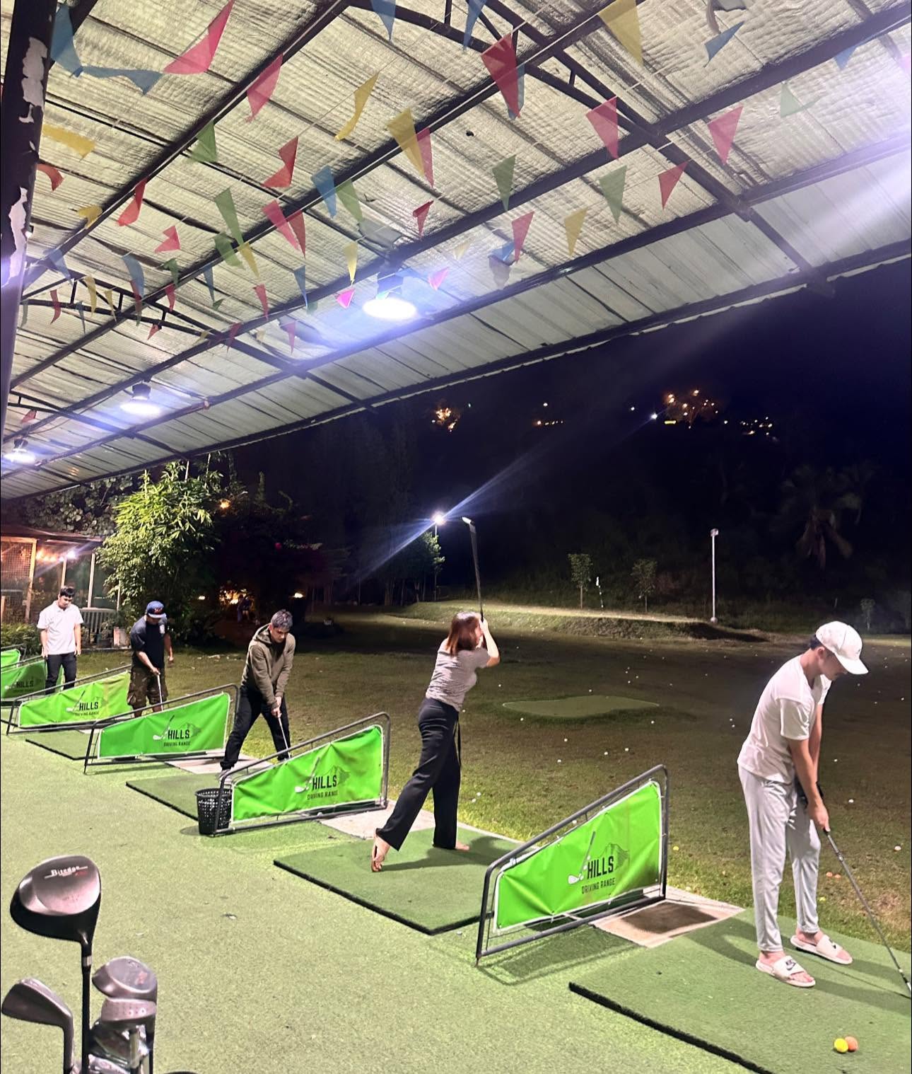 Golfers practicing at the lighted J-Hills driving range at night