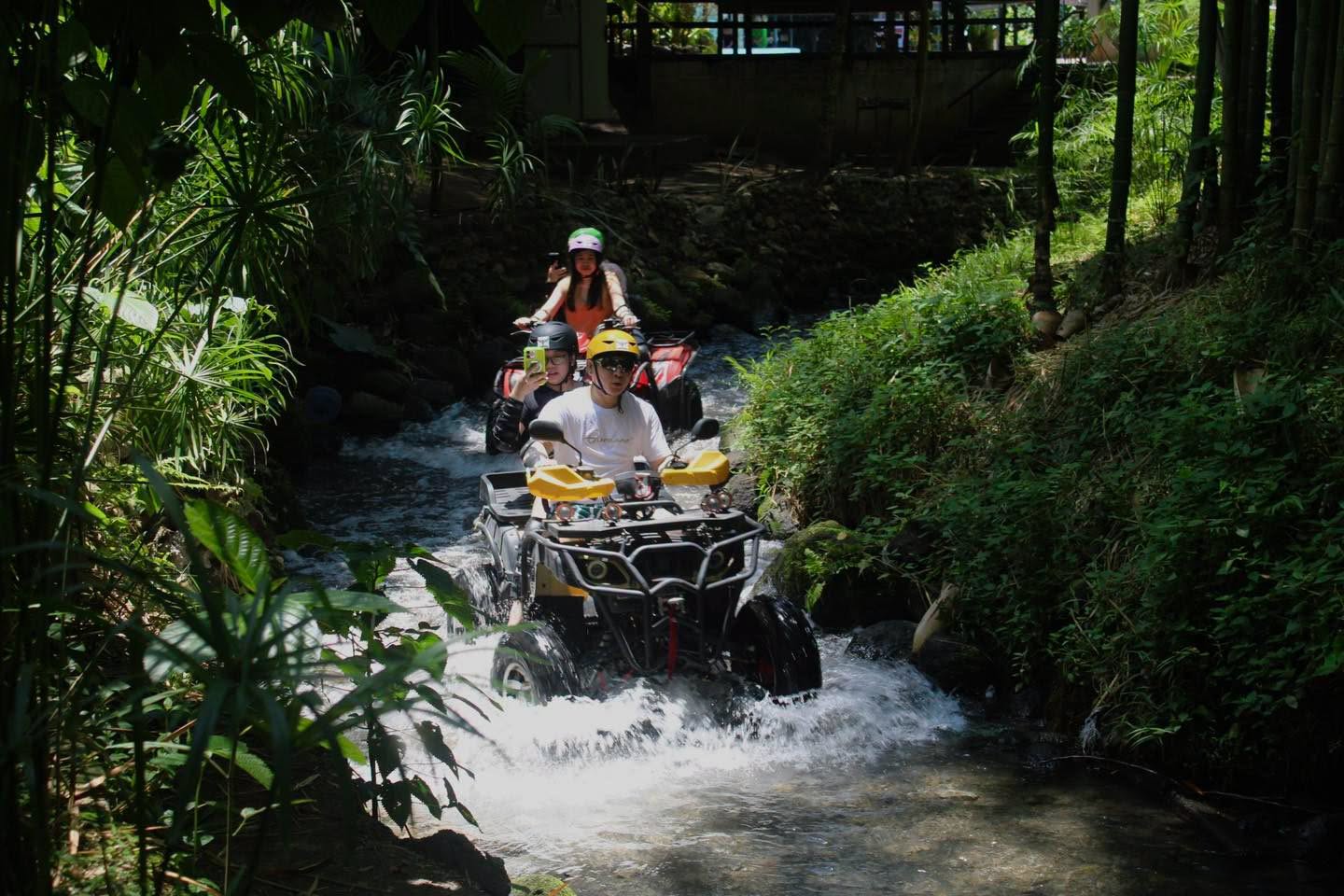 ATV riders passing through a tree-lined creek at River Ranch Resort