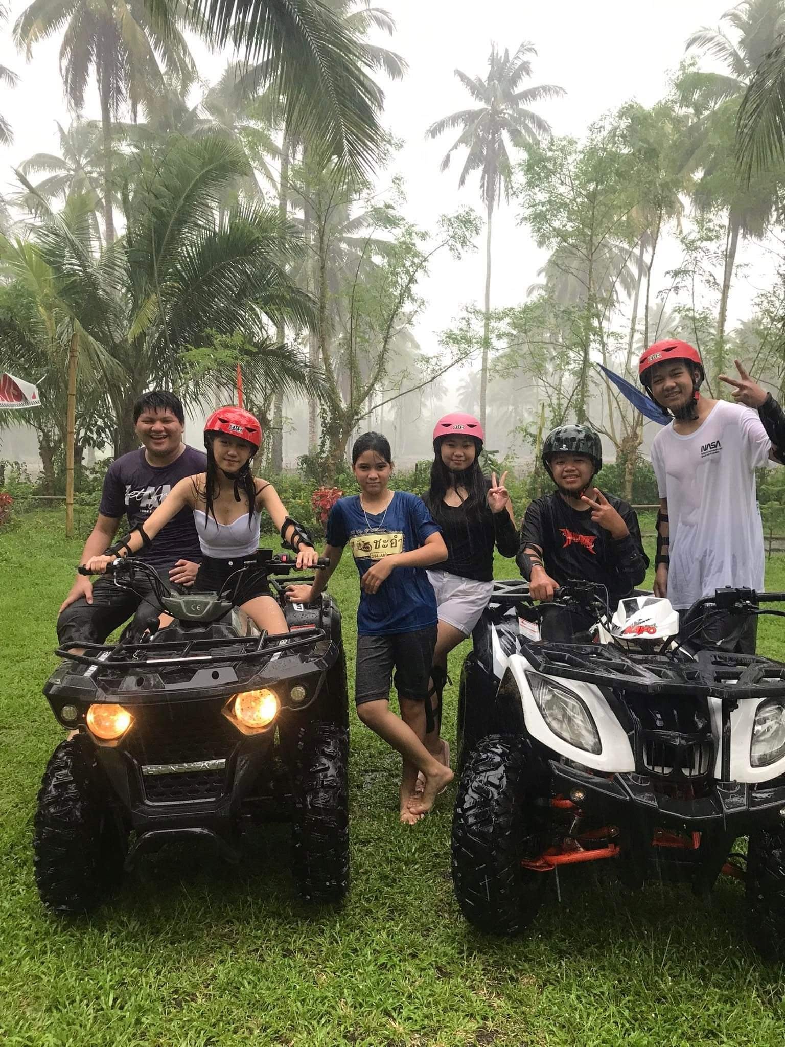 Group posing with ATVs among misty palms