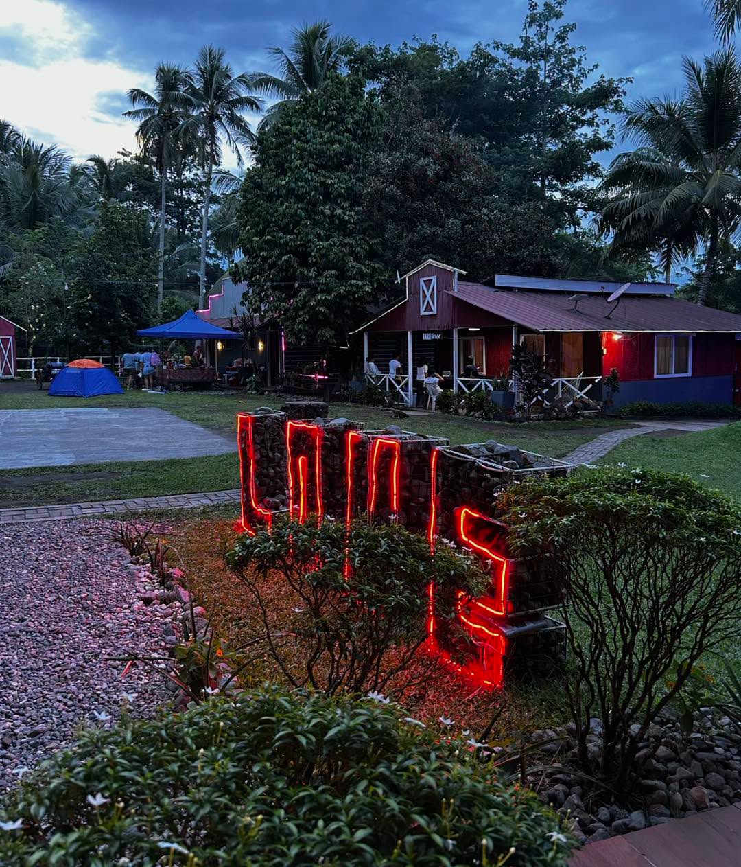 Red farmhouse and illuminated LOVE sign at dusk