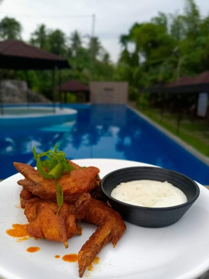 Chicken wings with a dipping sauce beside the pool