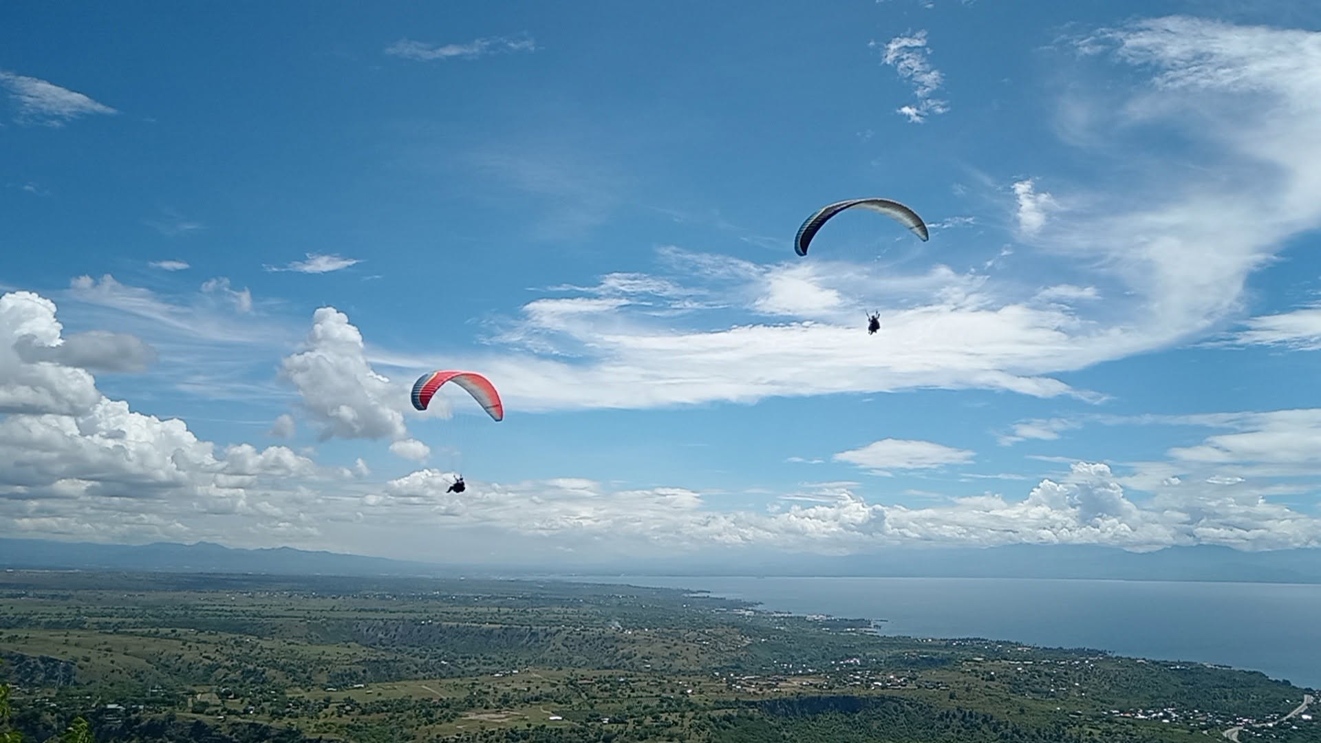Paragliders flying above the Sarangani landscape and Sarangani Bay