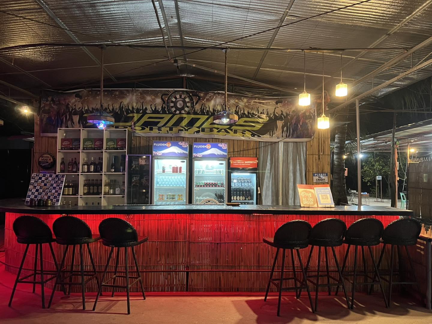Bar counter with red lighting and stools at T-James Sporty Bar