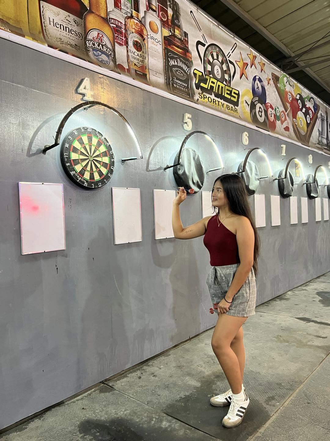 Darts player aiming at an illuminated board at T-James Sporty Bar