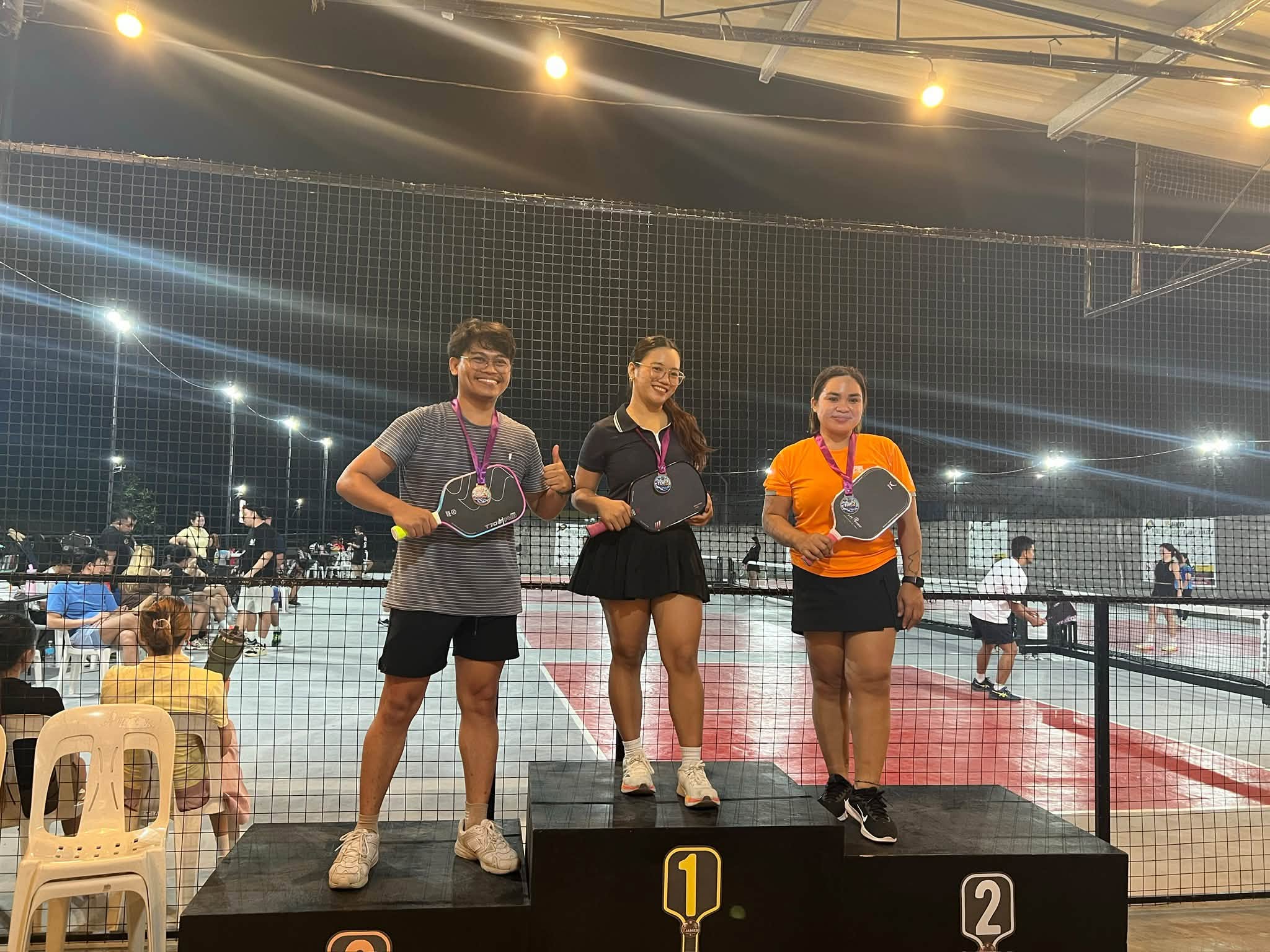 Pickleball medalists on a winners podium at T-James Sporty Bar