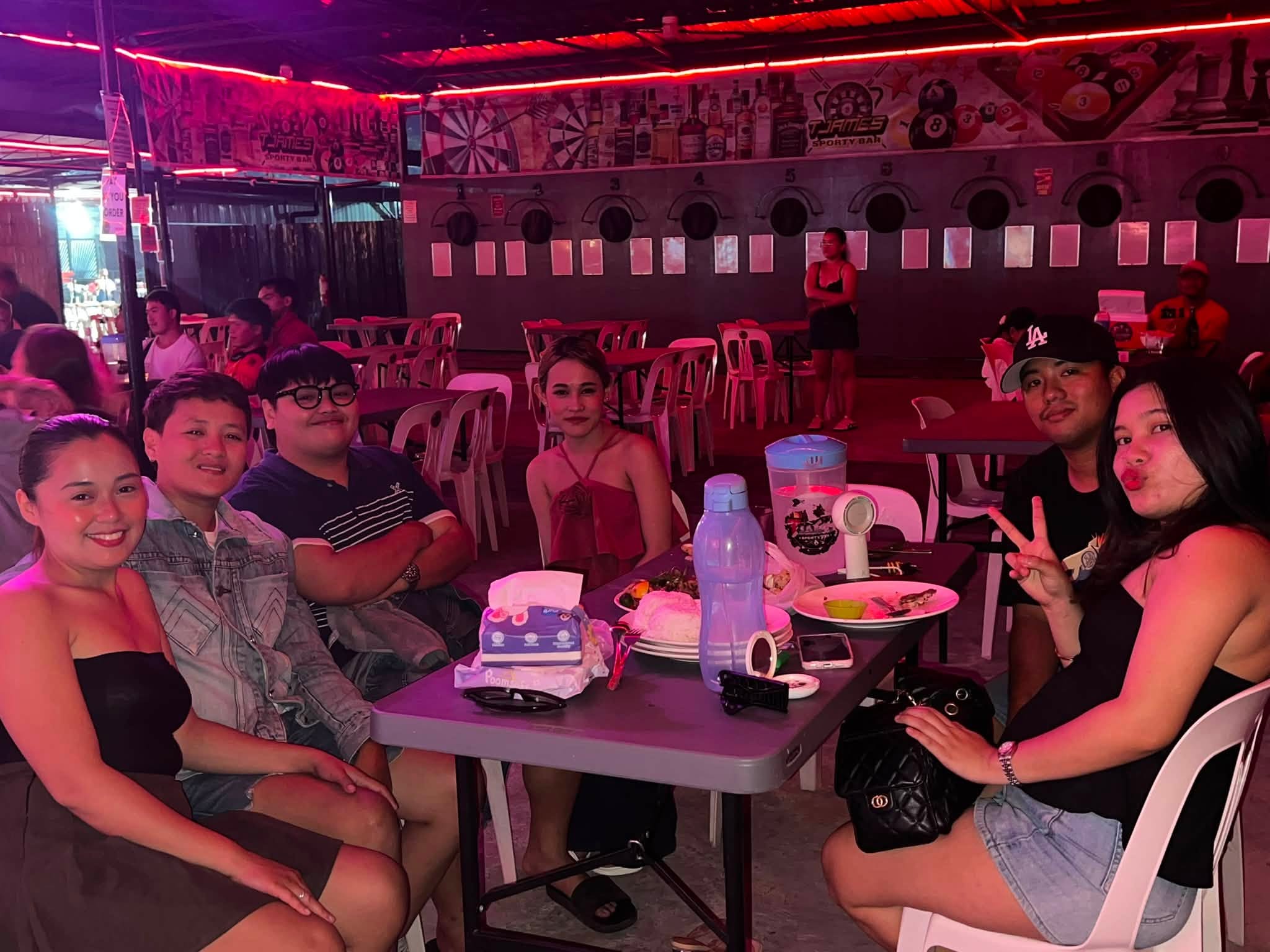 Friends sharing food and drinks in the seating area at T-James Sporty Bar